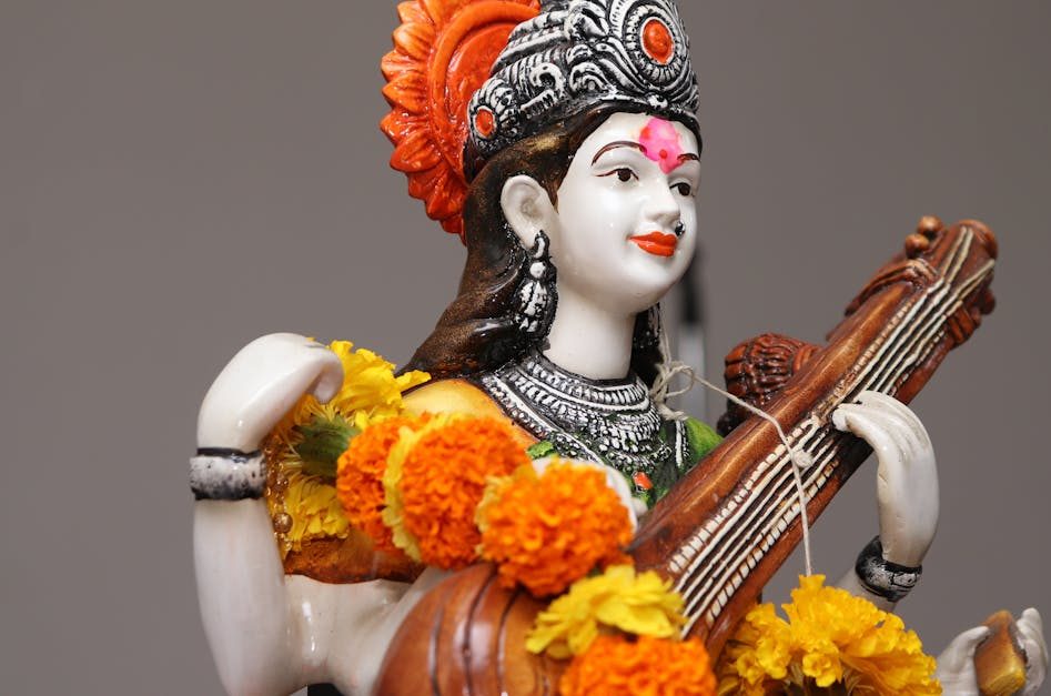 Close-up of a Saraswati statue adorned with vibrant marigold flowers, symbolizing wisdom and art.